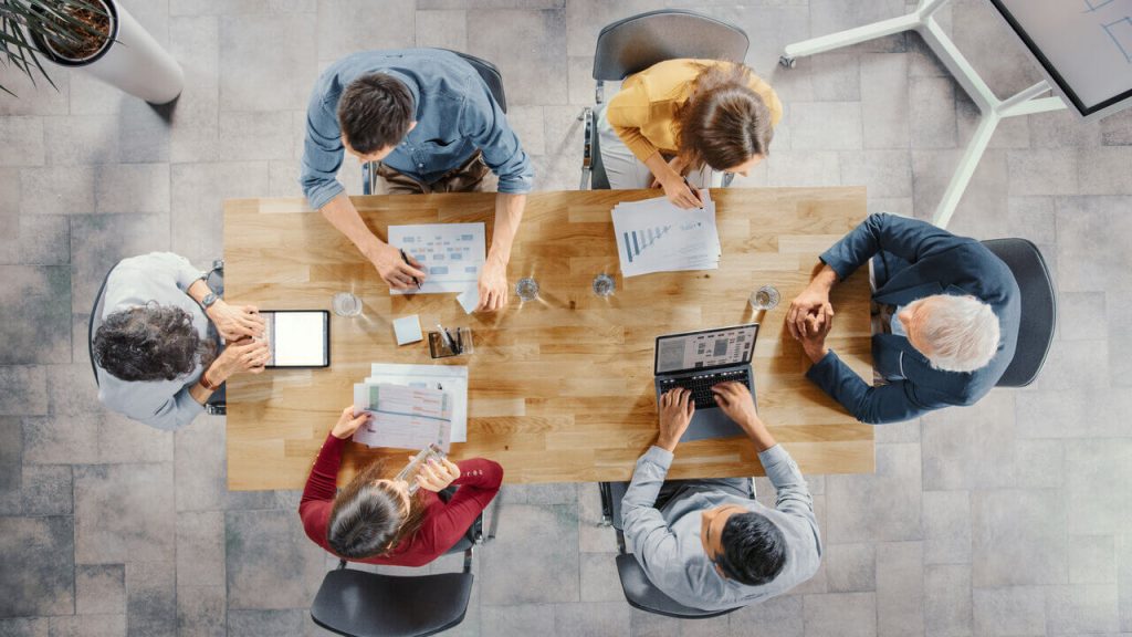 Image from above of a group of people meeting and working for a digital agency around a table