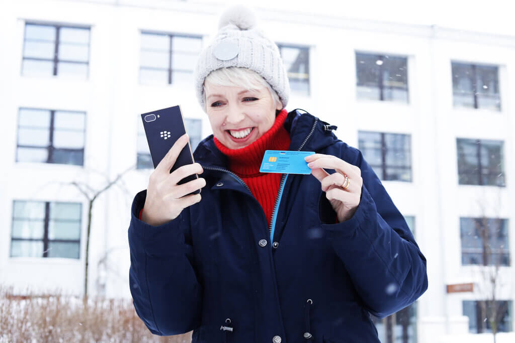 E-resident Vicky Brock in snowy Tallinn holding her mobile and e-Residency digital identity card