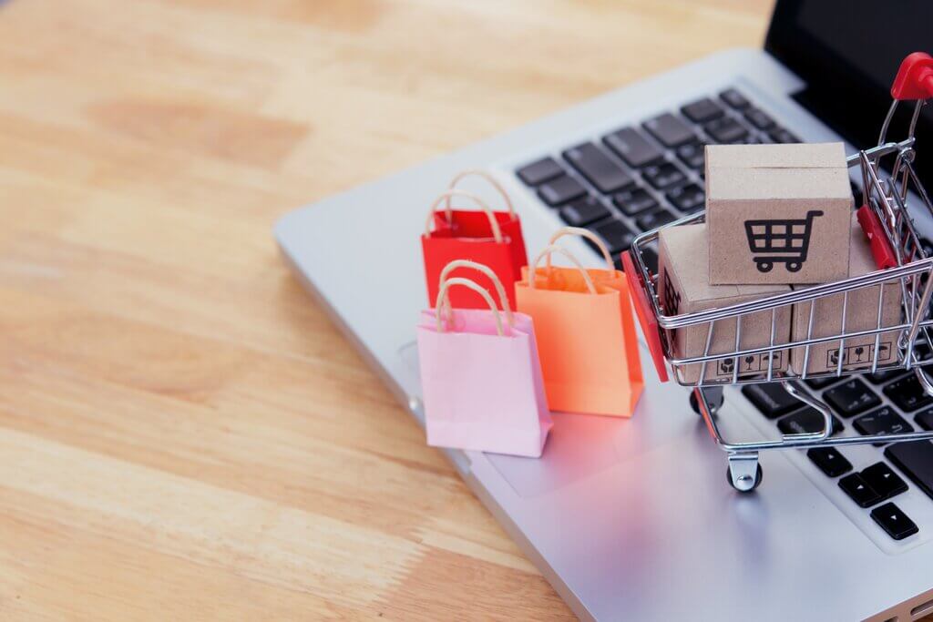 E-commerce business and shopping online: cardboard box with a shopping cart logo in a trolley and paper bag on laptop keyboard. Shopping service on The online web. offers home delivery