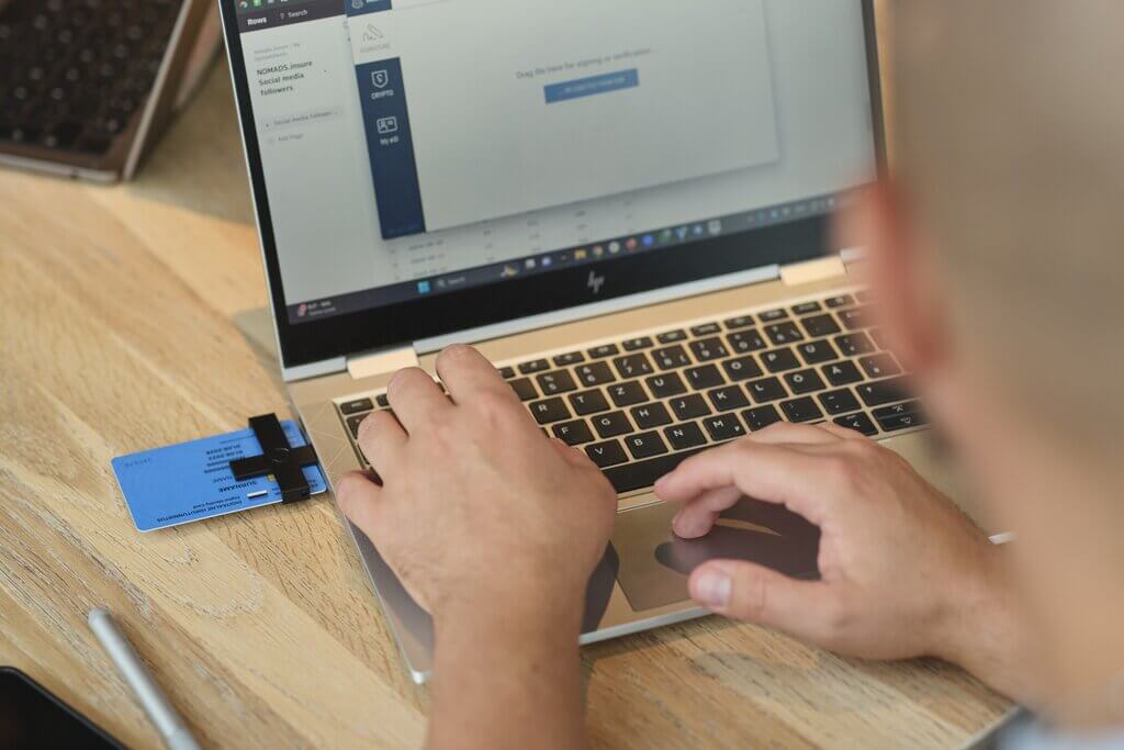 Man making electronic signatures with blue e-resident digital identity card connected to laptop